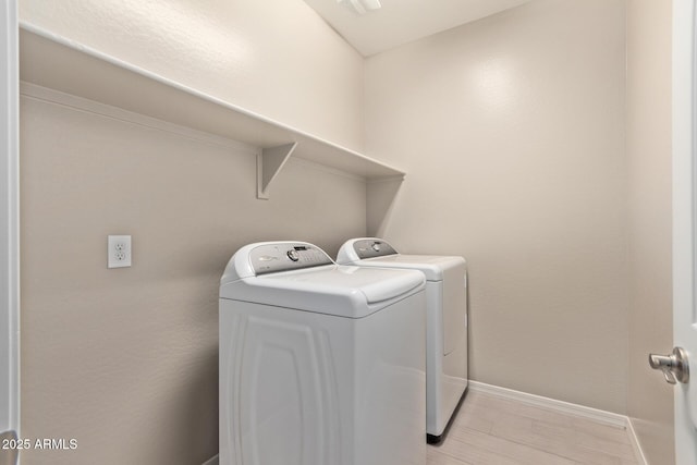 laundry area with laundry area, light wood-type flooring, washing machine and clothes dryer, and baseboards