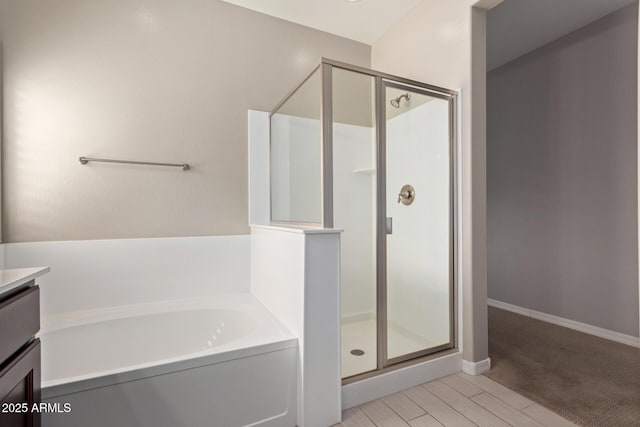 full bathroom featuring a garden tub, a shower stall, vanity, and wood finished floors