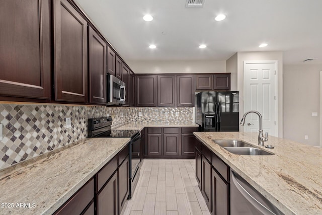 kitchen featuring light stone counters, tasteful backsplash, a sink, dark brown cabinets, and black appliances