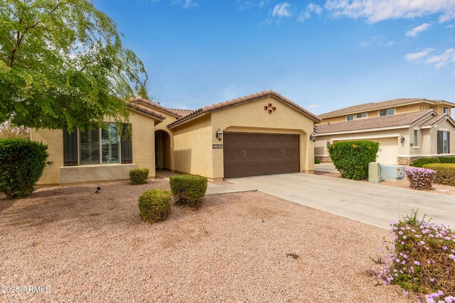 mediterranean / spanish home with a garage, driveway, a tiled roof, and stucco siding