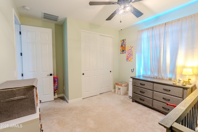 carpeted bedroom featuring ceiling fan, a closet, and a nursery area