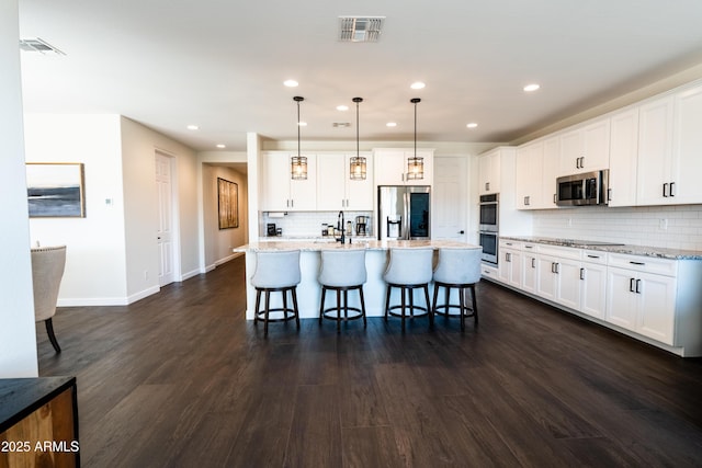 kitchen featuring pendant lighting, a center island with sink, white cabinets, and stainless steel appliances