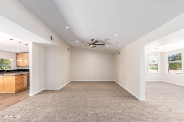 spare room with ceiling fan, light carpet, and sink