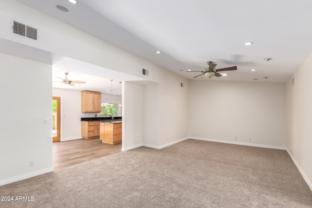 carpeted empty room featuring ceiling fan and sink