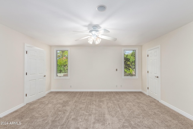 empty room featuring light carpet, a healthy amount of sunlight, and ceiling fan