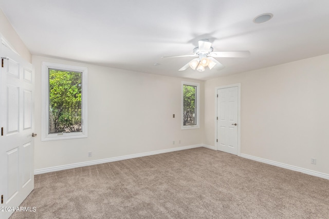 spare room with ceiling fan, light colored carpet, and plenty of natural light