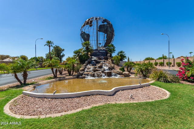 view of property's community with a yard and a garden pond