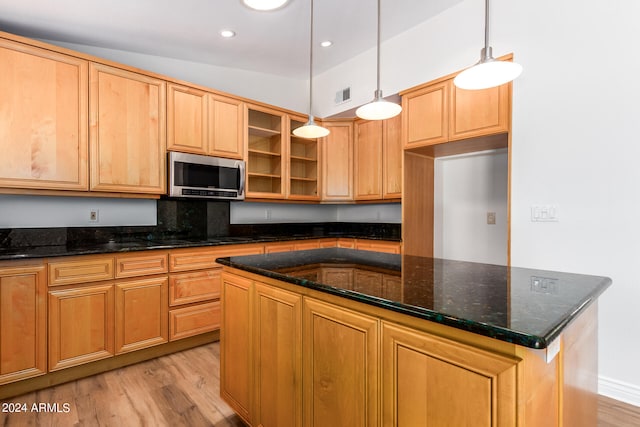 kitchen with a kitchen island, vaulted ceiling, decorative light fixtures, and light wood-type flooring