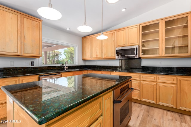 kitchen featuring light hardwood / wood-style flooring, a center island, stainless steel appliances, lofted ceiling, and dark stone counters