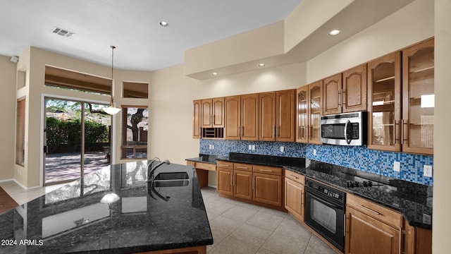 kitchen with dark stone countertops, sink, hanging light fixtures, and black appliances