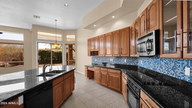 kitchen featuring dark stone counters, decorative light fixtures, sink, and black appliances