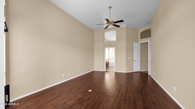 empty room with hardwood / wood-style floors, a towering ceiling, and ceiling fan