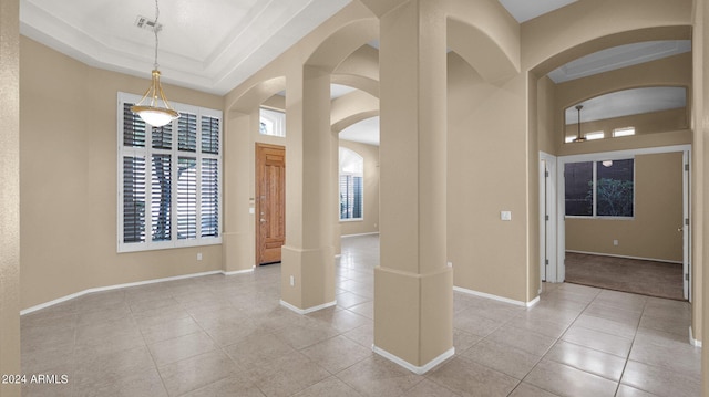 interior space with light tile patterned floors and a raised ceiling