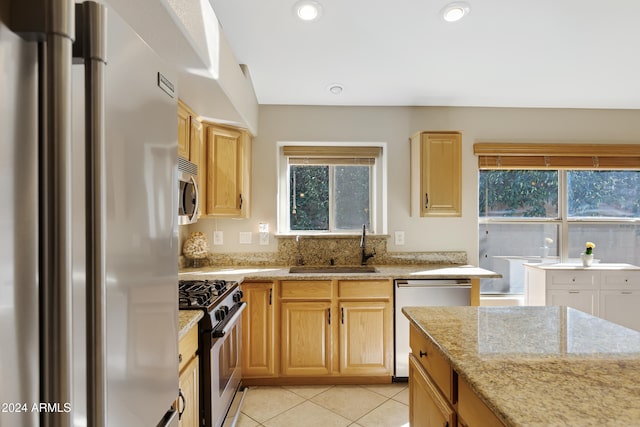 kitchen with light stone countertops, sink, light brown cabinets, stainless steel appliances, and light tile patterned flooring