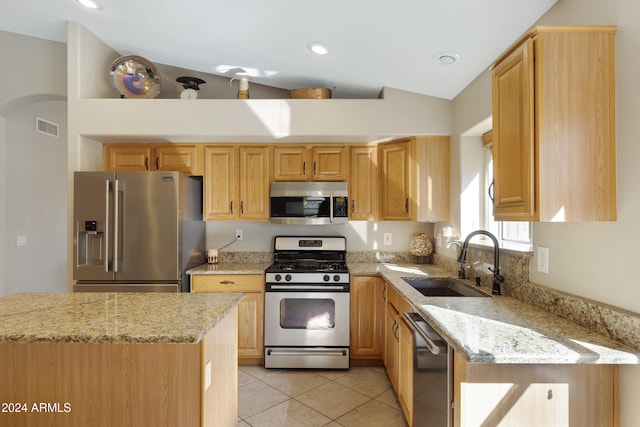 kitchen featuring light stone countertops, appliances with stainless steel finishes, vaulted ceiling, and sink