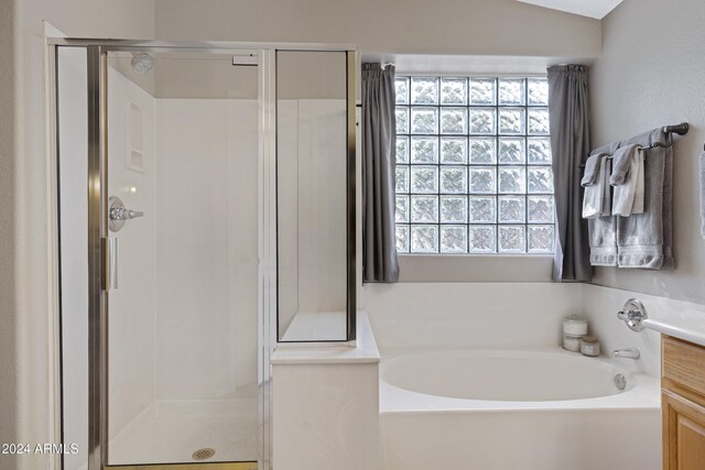 bathroom featuring vanity, independent shower and bath, and lofted ceiling