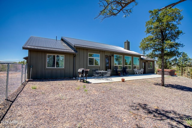 1014 Etta Ln, Show Low, AZ 85901 - rear view of property featuring a hot tub, board and batten siding, a chimney, a fenced backyard, and a patio area