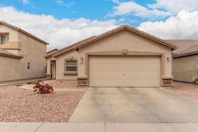 view of front of home featuring stucco siding, concrete driveway, a tile roof, and a garage