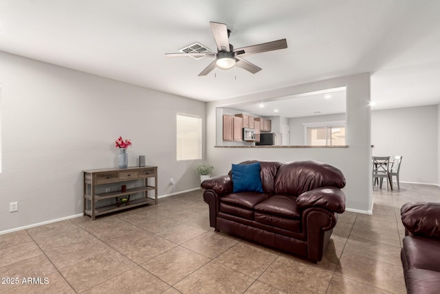 living area with light tile patterned flooring, visible vents, baseboards, and ceiling fan