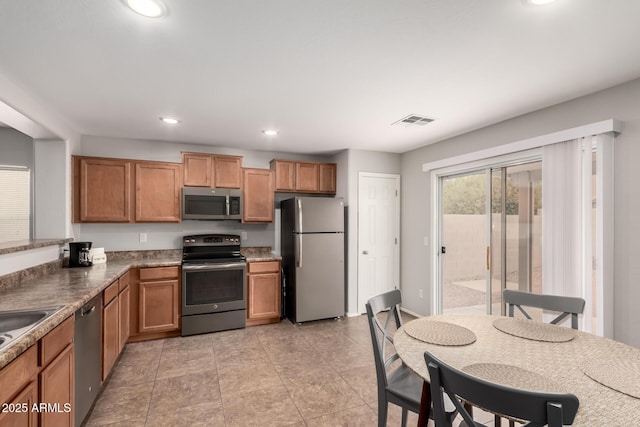 kitchen with visible vents, recessed lighting, stainless steel appliances, brown cabinetry, and light tile patterned floors