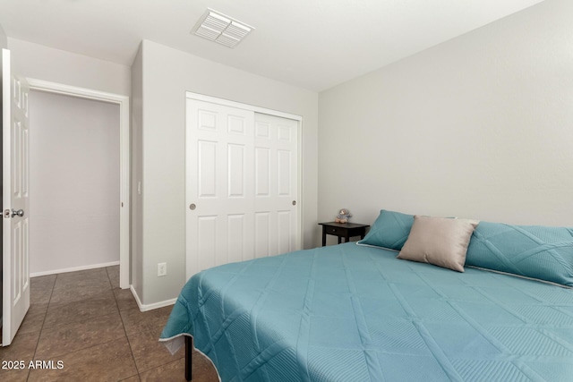 bedroom featuring a closet, visible vents, baseboards, and dark tile patterned flooring