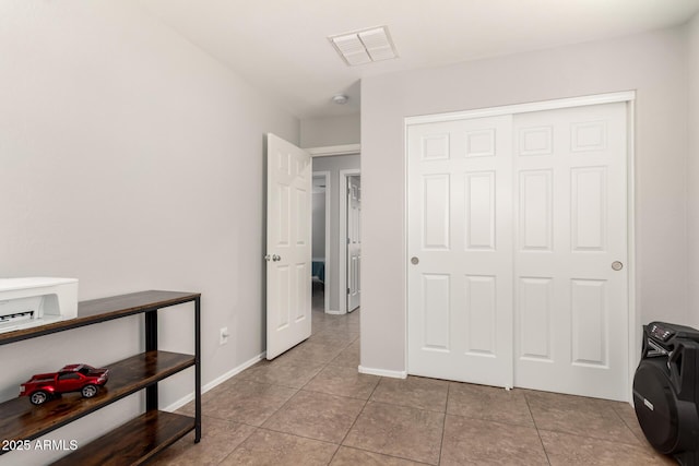 tiled bedroom featuring visible vents, baseboards, and a closet