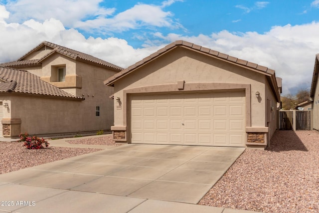 view of front facade featuring an attached garage, fence, driveway, and stucco siding