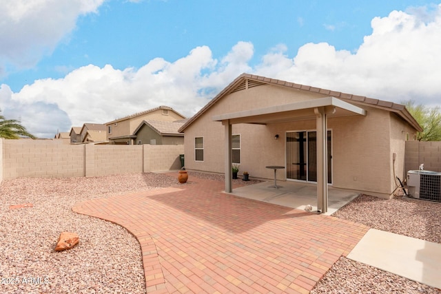 rear view of property featuring central air condition unit, a patio area, a fenced backyard, and stucco siding