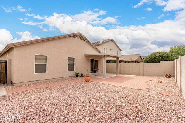 rear view of house featuring a patio area, stucco siding, and a fenced backyard