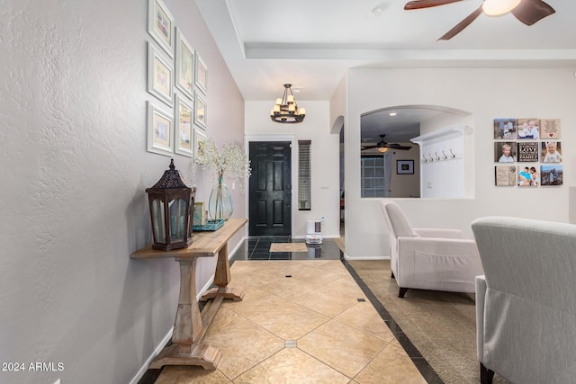 foyer entrance with tile patterned flooring and ceiling fan with notable chandelier