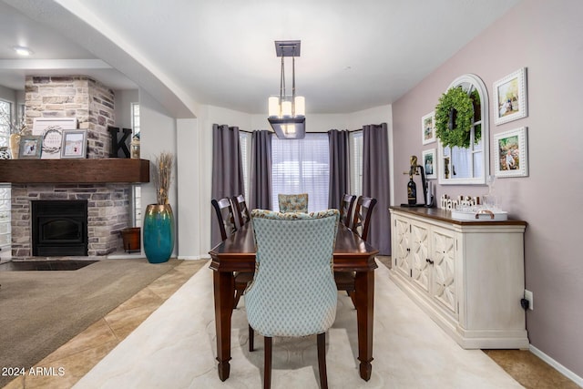 carpeted dining area with a stone fireplace