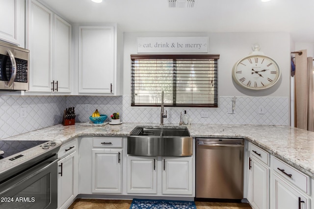 kitchen with light stone countertops, sink, white cabinets, and appliances with stainless steel finishes