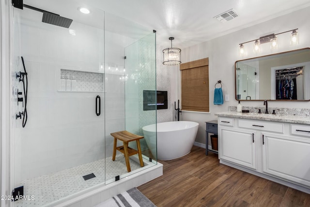 bathroom with hardwood / wood-style floors, vanity, an inviting chandelier, and separate shower and tub