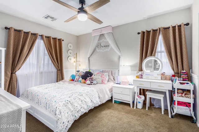 bedroom with ceiling fan, dark carpet, and multiple windows