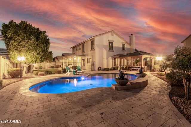 pool at dusk with a gazebo and a patio area