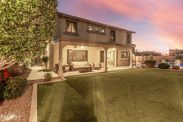 back house at dusk with an outdoor hangout area, a patio area, and a lawn