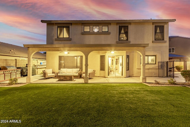 back house at dusk featuring outdoor lounge area, an outdoor kitchen, a yard, and a patio