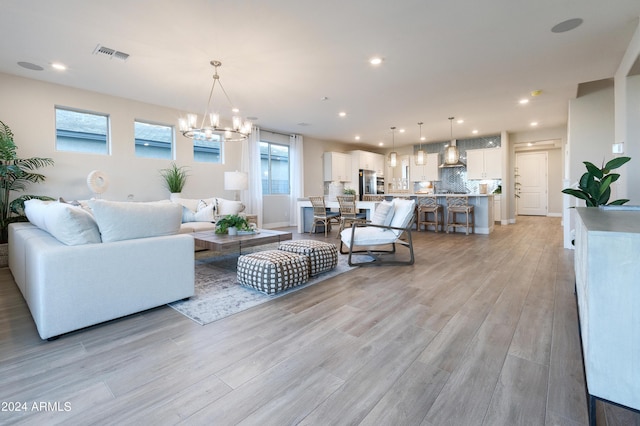 living room with an inviting chandelier and light hardwood / wood-style flooring