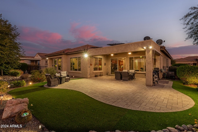 back house at dusk with a patio area and an outdoor hangout area