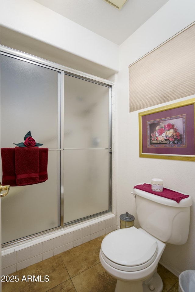 bathroom with tile patterned flooring, toilet, and a shower with shower door