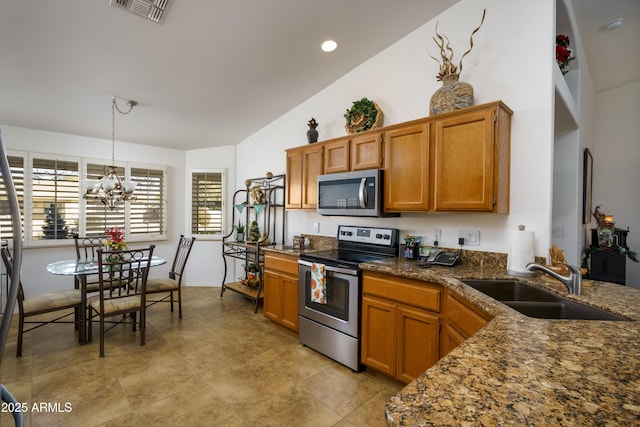 kitchen featuring pendant lighting, lofted ceiling, sink, a notable chandelier, and stainless steel appliances