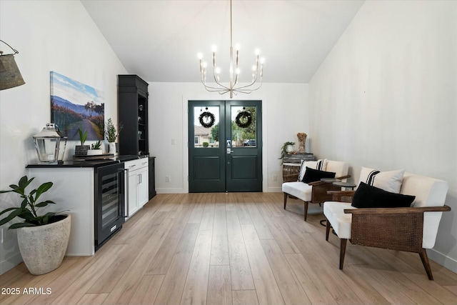 interior space featuring wine cooler, vaulted ceiling, french doors, light wood-type flooring, and a chandelier