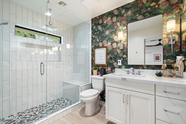 full bath featuring toilet, vanity, visible vents, a stall shower, and wallpapered walls