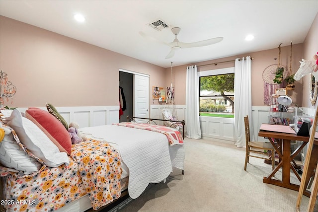 bedroom with a ceiling fan, wainscoting, light carpet, and visible vents