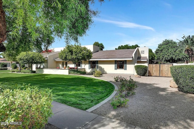 view of front of property featuring a front yard, fence, and stucco siding