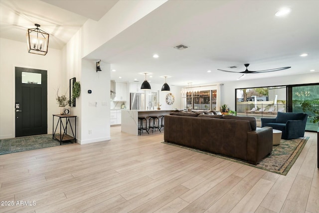 living area with recessed lighting, ceiling fan with notable chandelier, visible vents, baseboards, and light wood-style floors