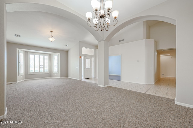 empty room featuring an inviting chandelier, light colored carpet, and vaulted ceiling