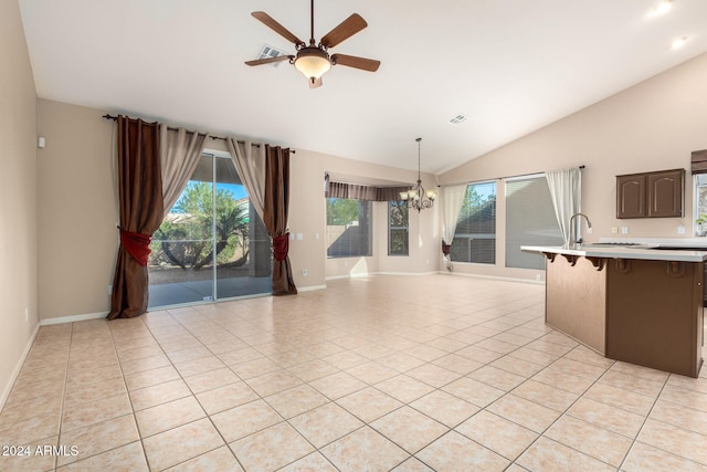 interior space featuring dark brown cabinets, ceiling fan with notable chandelier, vaulted ceiling, light tile patterned floors, and hanging light fixtures