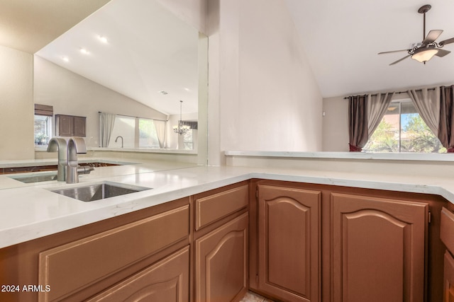 kitchen featuring kitchen peninsula, ceiling fan with notable chandelier, vaulted ceiling, and sink