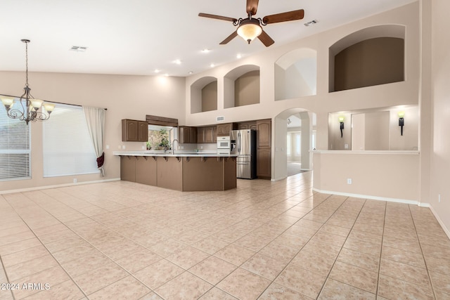 kitchen with ceiling fan with notable chandelier, dark brown cabinetry, sink, stainless steel fridge with ice dispenser, and light tile patterned flooring